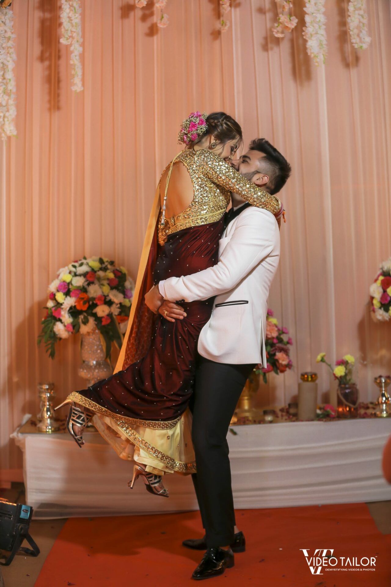 Young Indian Bride groom posing for photograph. Groom kissing the forehead  of bride. The couple is wearing traditional indian wedding dress which is  designer lehenga for bride and sherwani for groom. Stock-bilde |