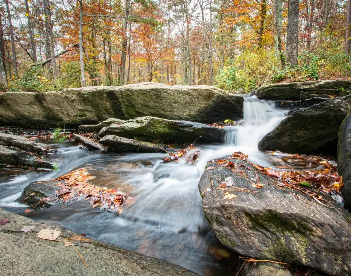 Chaeha falls small stream running down different escalations and levels of rocks with fall autumn leaves and forests in the background on Cheaha Mountain.