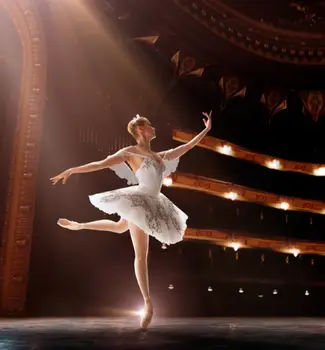 Ballerina dancing on stage in a white jeweled tutu dress in a Birmingham concert center.