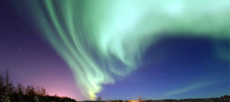 Northern lights at night in Alaska over snowy terrain.