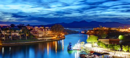 Lake Havasu City at night in Arizona with a dark cloudy sky and bright lights from buildings and streets.
