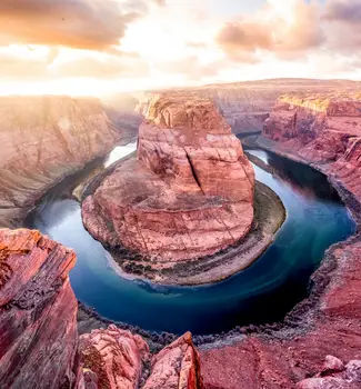 Top view of Horseshoe Bend in Page, Arizona with a river flowing in a circular shape between sedimentary mountains and rocks.