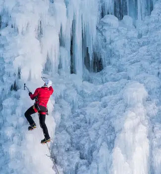 Man in red coat ice climbing in Ouray, Colorado free park in winter.