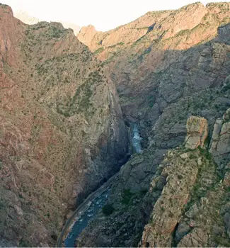 View from the bridge on Royal Gorge in Colorado with a small white water rapid flowing through two rocky mountains.