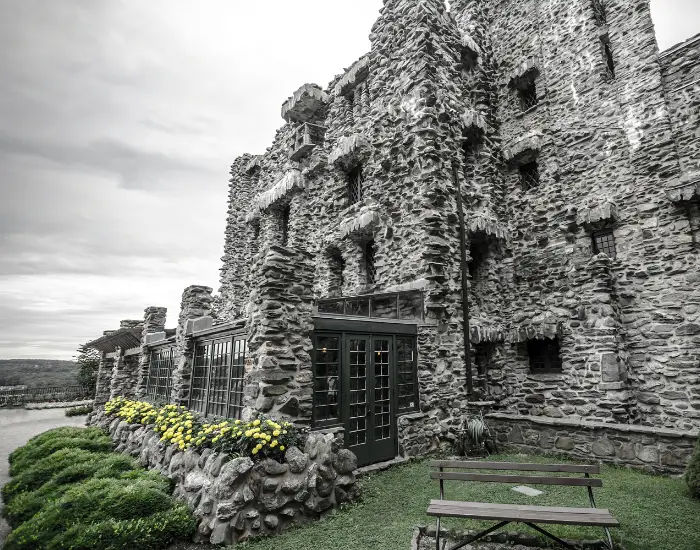 Gillette Castle in Connecticut on a cloudy dark day with an indoor patio and green bushes.