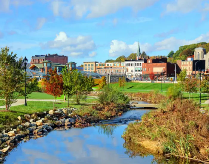 Meridon in New Haven County, Connecticut with a river flowing through a nature filled park and city buildings in the background.