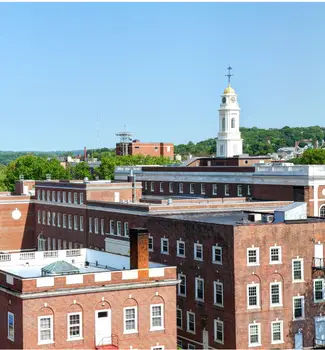 Overview of Waterbury in Connecticut with a large white church tower and red brick buildings between green forestry.