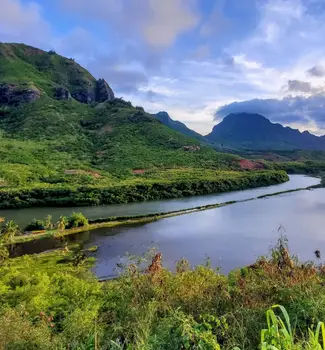 Green scenic overview of Hawaii islands and mountains over a body of water.