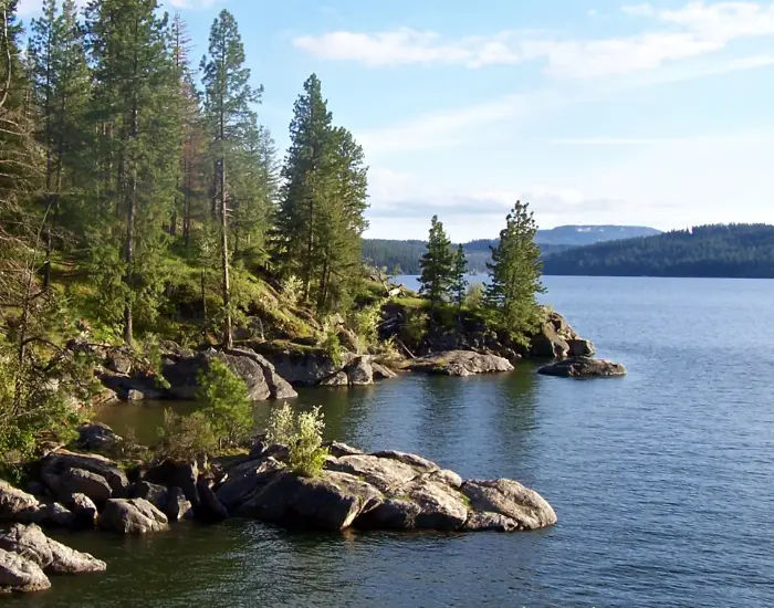 Coeur D'alene Lake in Idaho on a summer day with clear skies with land rocks sticking out.