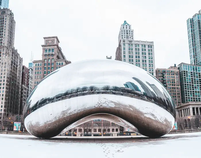 The Cloud Gate in Millennium Park in Chicago, Illinois with a silver reflective bean monumental structure reflecting buildings.