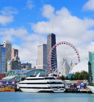 Chicago's Navy Pier in Illinois coastline with a cruise boat, yacht, buildings, and ferris wheel on a sunny day.