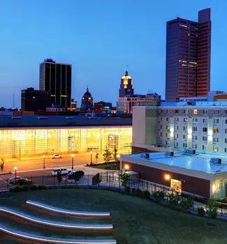 Downtown Fort Rayne at night with buildings and illuminated steps on a field of grass.