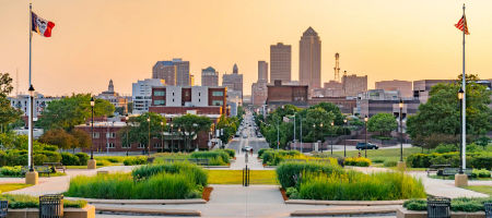 Des Moines, Iowa city state skyline at sunset with flags flying and looking down a busy street.