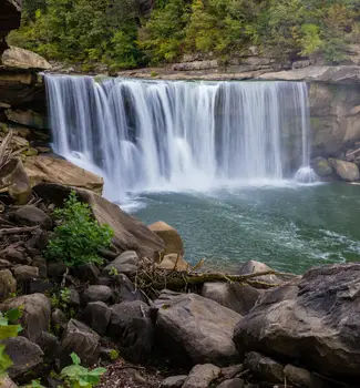 travel nurse jobs lexington ky Cumberland falls in Corbin Kentucky with water flowing between nature with trees and rocks.