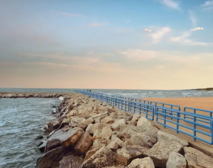 Breakwater Lake in Michigan-Holland, Michigan with rocks and a walking path stretching out into the wave filled lake at dusk.