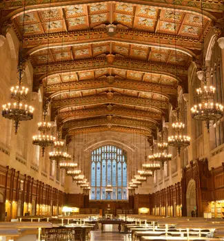 Inside a law school library in the University of Michigan in Ann Arbor with chandeliers, architecture, and tables lined up.