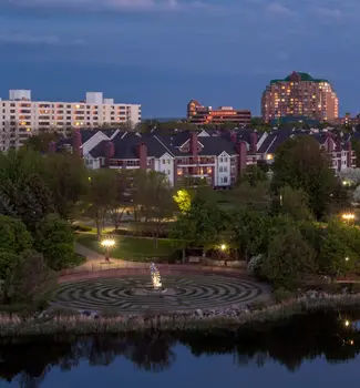 Bloomington skyline at blue hour with circular grass maze surrounding a sculpture in front of buildings.