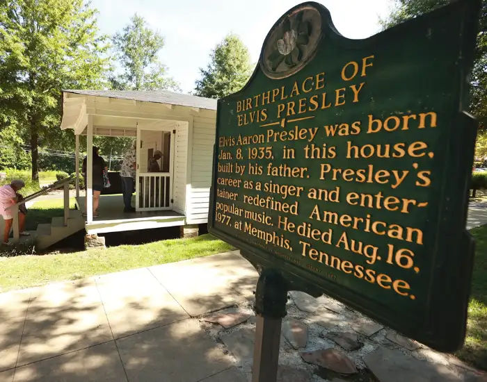 Elvis Presley Birthplace & Museum sign with people walking into the building in Mississippi.