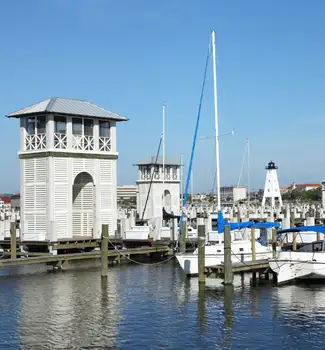 Boats docked on shore at the Gulfport, Mississippi port on a sunny day in front of a white building.