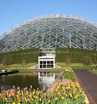 Climatron botanical garden in St.Louis, Missouri with a green house dome encased with leafy green natural plants and tulips.