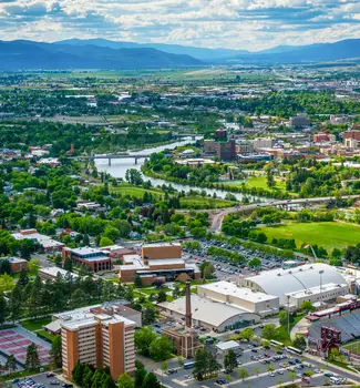 Aerial view of Missoula, Montana with a diver running through the city and mountains in the background.