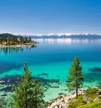 Lake Tahoe near Sand Harbor in Nevada with crystal clear blue waters and snowcapped mountains in the background.