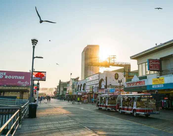 Downtown Atlantis City boardwalk in new Jersey at sunset with people walking and shopping.