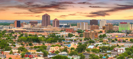 New Mexico Albuquerque city skyline at dusk with buildings and trees mixed together.