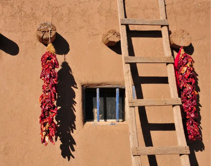 Red peppers and wooden ladder at the side of a Pueblo styled house in Taos, New Mexico.