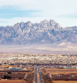 Las Cruces, New Mexico aerial view on a sunny day with roads leading into the city in front of a backdrop with mountains.