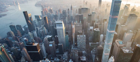 New York City skyline in cloudy foggy weather with warm sun rays.