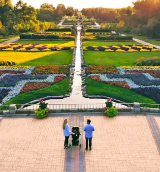 Travel nurse couple and child standing at the top of a building patio in the International Peace Garden State Garden admiring the sunset and geometric flower beds with a pond running down the middle.