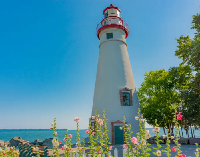 Marblehead Lighthouse State Park in Ohio during the day behind a row of pink spring flowers.