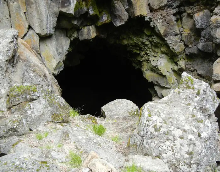 Lava River Cave entrance leading into a dark crevice in Oregon during the day.