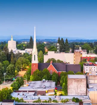 Salem, Oregon city skyline at twilight with buildings and streets lined with trees.