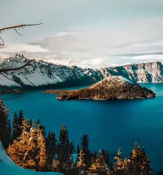 Aerial view of Crater Lake in Oregon with snow-capped mountains surrounding a body of water.