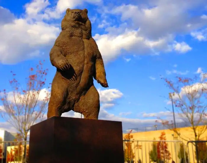 Looking up at a large bear Kodiak sculpture in Providence in autumn on a partly cloudy day.