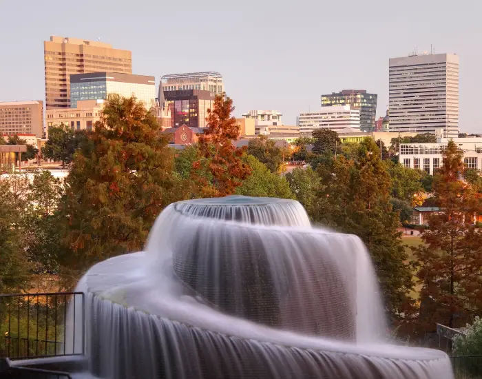 Fountain running in Finlay Park while overlooking the cityscape and trees of Downtown Colombia, South Carolina in autumn.