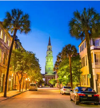 Charleston, South Carolina city scape with historic French Quarter at twilight lit up with lights.