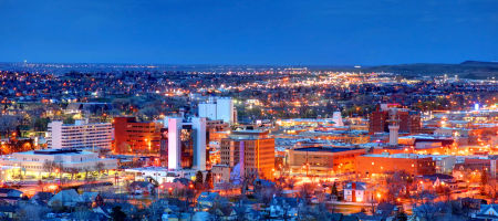 Aerial skyline view of Rapid City, South Dakota in the Pennington County at night with buildings lit up.