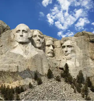 Presidential sculpture of four heads carved in a stone mountain on a hill at Mount Rushmore National Monument in South Dakota.
