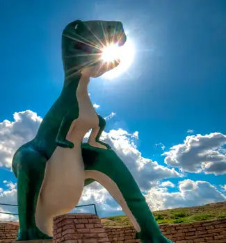 Looking up at a green prehistoric model in Dinosaur Park with the sun shining through the t-rex's mouth in South Dakota.