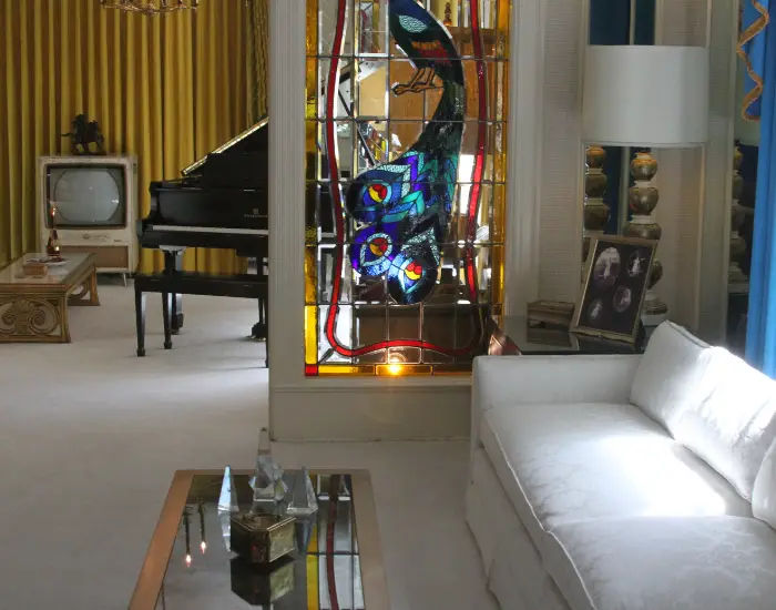 Elvis Presley's home in Elvis' Graceland estate Tennessee with a living room, stained glass divider, and piano.