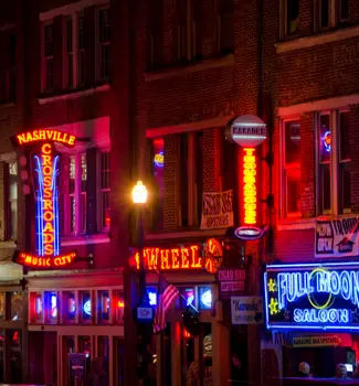 Downtown Nashville, Tennessee at night with colorful neon lights and signs on buildings.