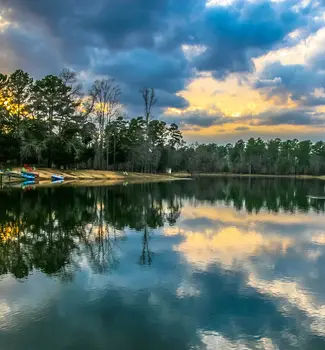 Overwater view of an East Texas Lake close to Caddo Lake with kayaks on the shore and plenty of greenery and trees in the background.