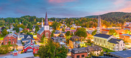 Montpelier, Vermont city skyline at dusk with buildings lit up and trees spread throughout the town.