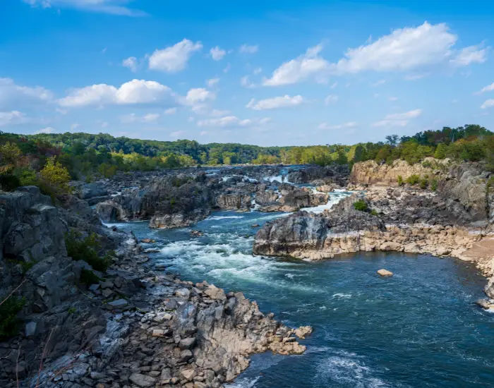 Wide angle shot of Great Falls Potomac Waterfall in Fairfax, Virginia with white water rapids forming between sedimentary terrain.