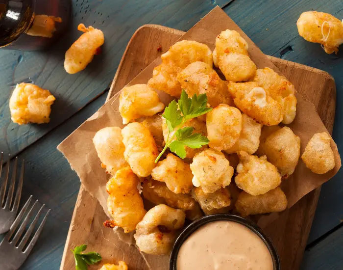 Beer battered cheese curds with dipping sauce served on a table from Mars Cheese Castle in Wisconsin.