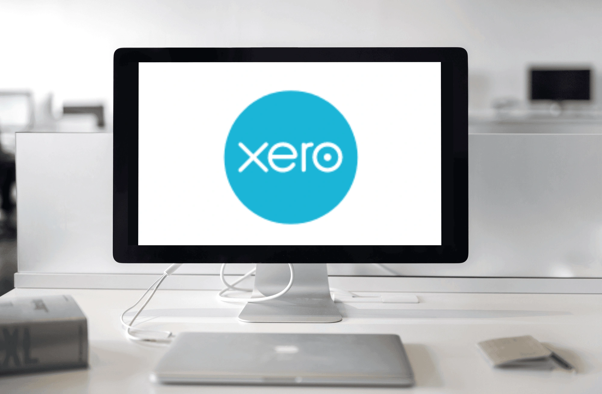 Picture of laptop and computer screen with Xero logo in office