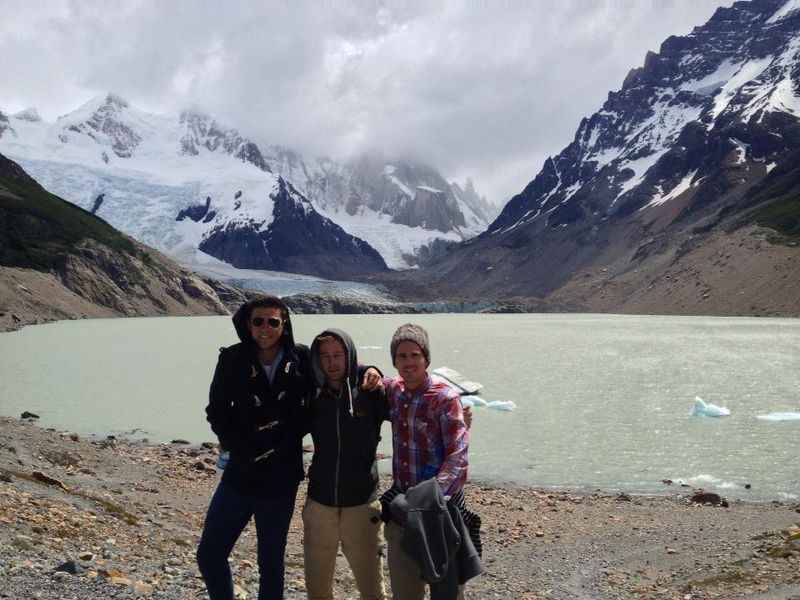 three men standing in front of a lake